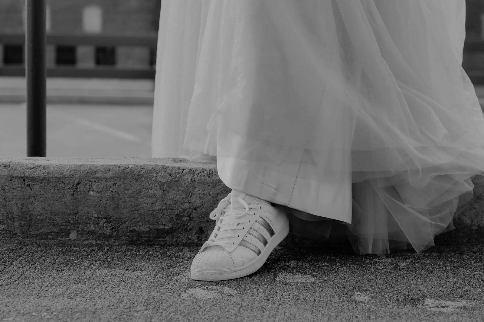 White sneakers peeking out from under the bride's tulle dress