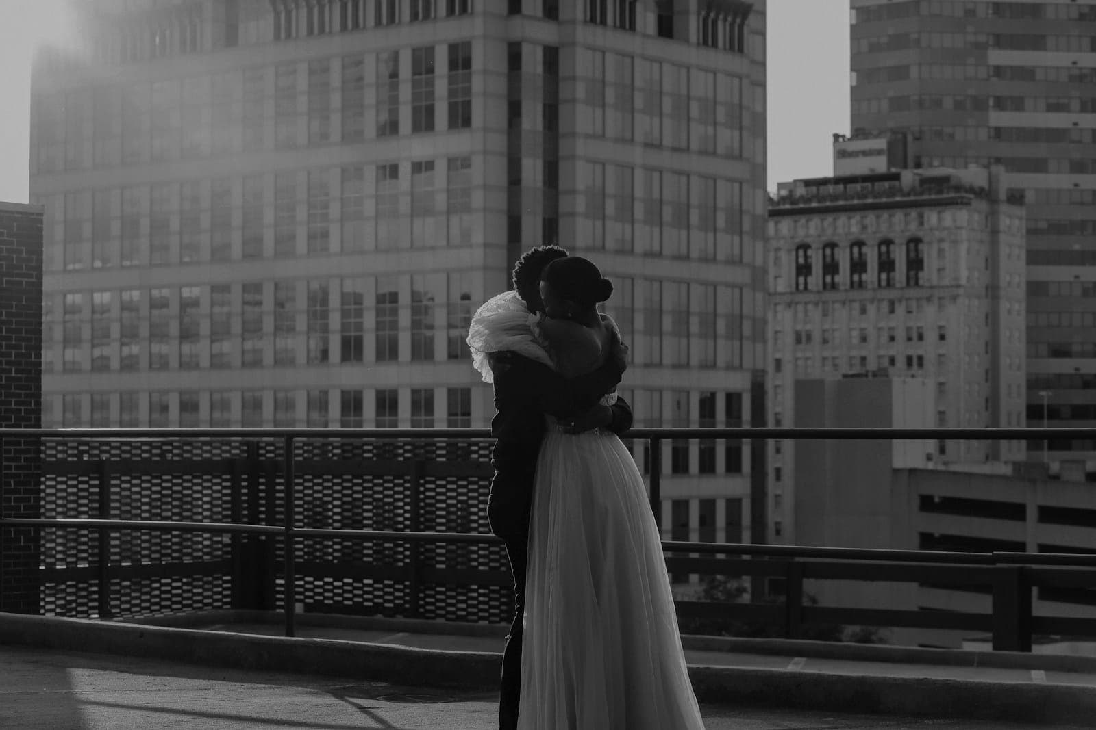 The couple wrapped in a hug on a city sidewalk, sun low behind them