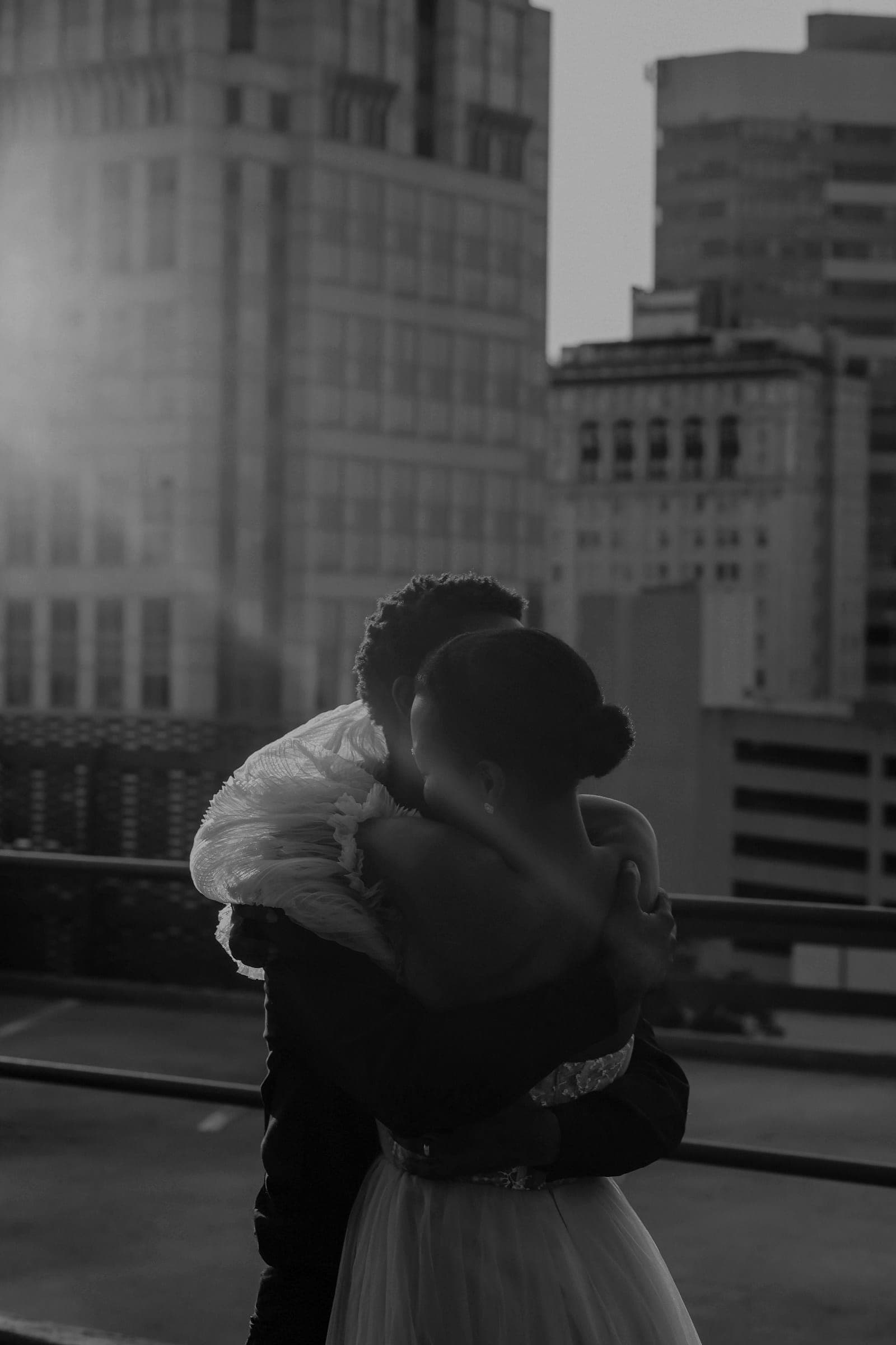 The couple holding each other close, tulle draped over his shoulder